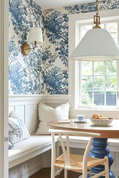 a dining room with blue and white wallpaper on the walls next to a window