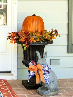 a statue of a rabbit sitting next to a planter with a pumpkin on it