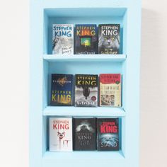 a blue book shelf filled with books on top of each other in front of a white wall