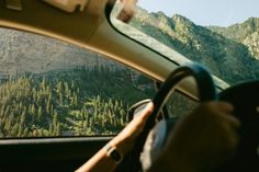 the view from inside a car looking at mountains and trees