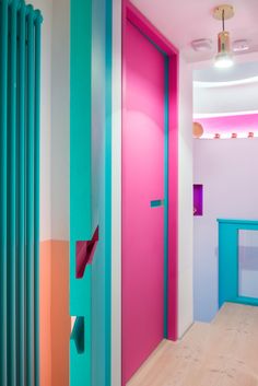 the interior of a brightly colored room with pink, blue and green doors