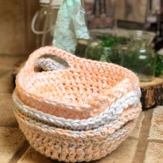 a crocheted basket sitting on top of a wooden table next to glass jars