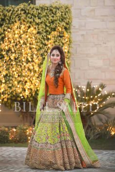 a woman in an orange and green lehenga