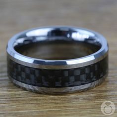 a black and silver wedding band on top of a wooden table