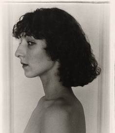 black and white photograph of a woman's head with curly hair, looking off to the side