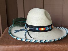 The Raindancer starts with a Mexican soft palm Gus hat body that has a 4" brim and 5 1/2" crown. Hand laced in black and turquoise leather lace. The beaded hatband has a rainbow of colors and is mounted on black suede. The back of the band has a deer antler bead for accent. Large antiqued Sunburst Concho with faux turquoise stone. A massive barred turkey feather dyed in turquoise completes the hat. All hats are made to order. Allow up to 4 weeks for your hat to ship. Adjustable Bohemian High Crown Hat Bands, Traditional Brimmed Hats For Western-themed Events, Custom Costume Hat With High Crown And Adjustable Fit, Custom High Crown Adjustable Costume Hats, Adjustable High Crown Multicolor Hat, Adjustable Multicolor High Crown Hat, Traditional Black Hat Bands For Festival, Turquoise Curved Brim Hat Band For Beach, Artisan Turquoise Hats For Western-themed Events