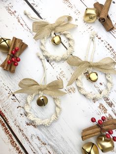 three christmas wreaths with bells and twine tied to them on a white wooden surface