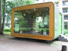 a green building sitting in the middle of a park