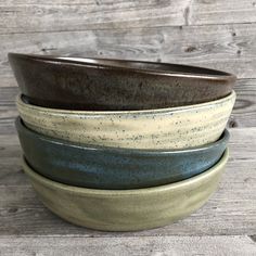 four bowls stacked on top of each other in different colors and sizes, sitting on a wooden surface