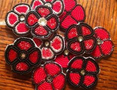 several red and black beaded buttons sitting on top of a wooden table