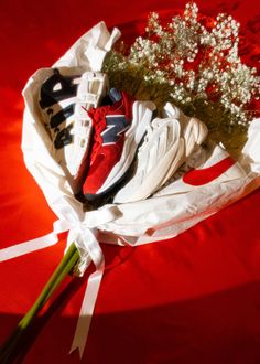 a bouquet of flowers and sneakers on a red surface