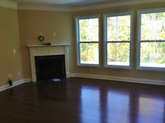 an empty living room with hardwood floors and two windows