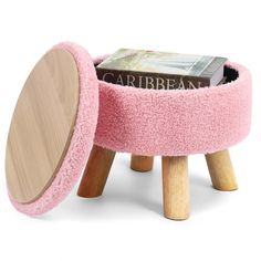 a pink stool with a book on top and wooden legs in the shape of a footstool