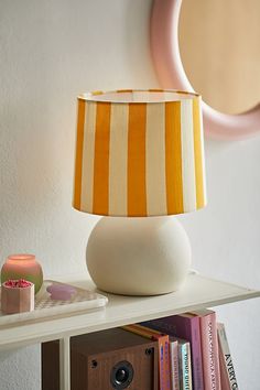 a lamp sitting on top of a white table next to a book shelf with books