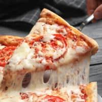 two slices of pizza being cut with a knife and fork