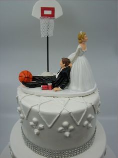 a wedding cake with a bride and groom laying on top of it next to a basketball hoop