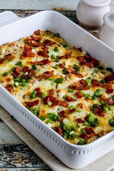 a casserole dish with bacon, green onions and cheese in it on a table