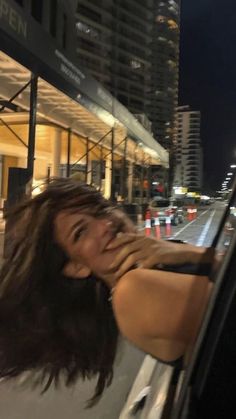 a woman leaning out the side of a car window at night with her hand on her face