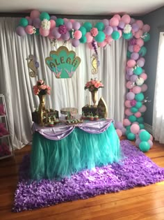 the table is set up for a little mermaid birthday party with balloons and streamers