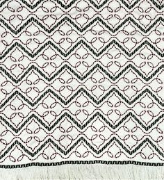 a black and white rug with an intricate design on the bottom, along with fringes