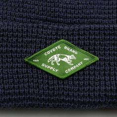 a close up view of the label on a blue beanie hat that says coyote brand supply company