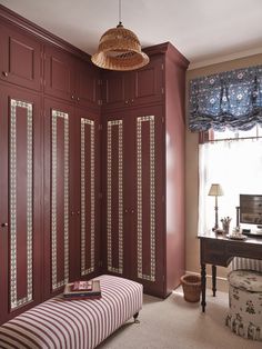 a bedroom with red walls and white carpeted flooring, built in wardrobes