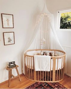 a baby crib in the corner of a room with a rug and pictures on the wall