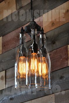 three light bulbs are hanging from the ceiling in front of a wooden wall with wood planks