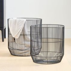 two black wire baskets sitting on top of a wooden floor