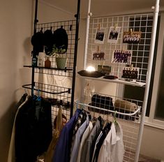 a rack with clothes hanging on it in front of a window and a wall mounted shelf