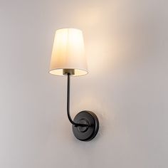 a wall light with a white shade on it's side and a black arm