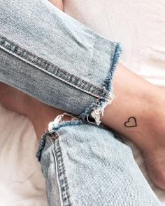 a person with a small heart tattoo on their left leg, laying down in bed