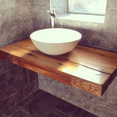 a white bowl sitting on top of a wooden counter next to a sink in a bathroom