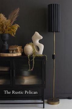 a black cabinet with a lamp, vases and other items on top of it