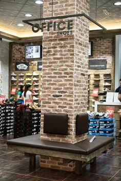 a brick pillar in the middle of a store with people shopping behind it and shelves full of shoes