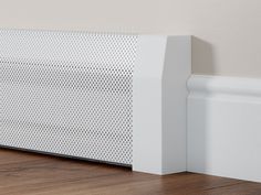 a white radiator sitting on top of a wooden floor next to a wall