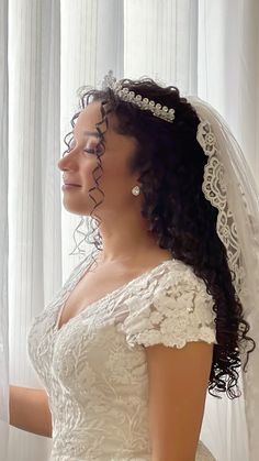 a woman in a wedding dress looking out the window