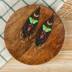 two beaded black cats sitting on top of a wooden plate