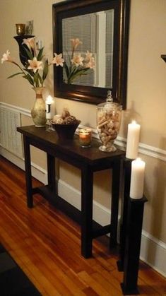 a table with candles and flowers on it in front of a mirror, next to a candle holder