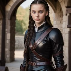 a young woman dressed in black and brown is standing near an archway with her hands on her hips