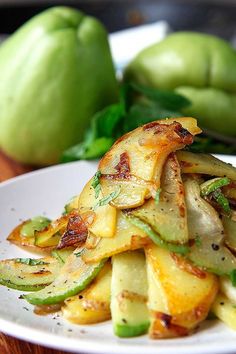 a white plate topped with sliced up vegetables on top of a wooden table next to an apple