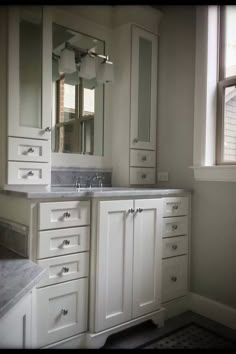 a bathroom with white cabinets and marble counter tops