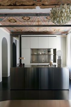 a kitchen with an island and chandelier hanging from it's ceiling above the counter