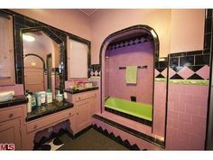 a bathroom with pink and black tile, green bathtub, sink, mirror and shower curtain