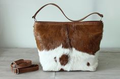 "COWHIDE PURSE, COWHIDE Handbag, Leather Tote Bag. Country Tote Bag in Calf Hair Brown and White Designer Bag, Sling Bag, Zipper Top Bag. This fabulous brown white fur goat leather bag is a serious show stopper. Gorgeous caramel and white cowhide patches on this superb handcrafted leather tote / bucket bag in dazzling brown and white calf fur shoulder bag. Smart additions includes internal pockets for phones and sun glasses plus a free zippered coin purse perfect for lipstick and other small ite White Rectangular Hobo Bag With Leather Handles, White Rectangular Hobo Bag With Dust Bag, White Hobo Bag For Everyday Use, Luxury White Hobo Bag With Leather Handles, White Leather Handheld Bucket Bag, White Handheld Leather Bucket Bag, White Pouch Hobo Bag, White Leather Pouch Hobo Bag, White Crossbody Hobo Bag With Handles