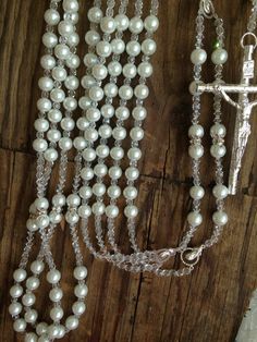 a rosary with white pearls and a crucifix hanging from it's side