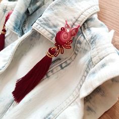 a white shirt with red tassels on it and a pair of earrings hanging from the back