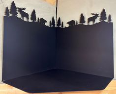 an open book with paper cut out of it and animals in the woods on top