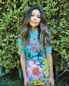 a woman standing in front of some bushes