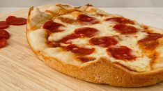 a pepperoni pizza sitting on top of a wooden cutting board